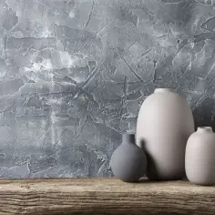 Szare wazony na drewnianej półce pod tynkiem strukturalnym. Zastanawiasz się, ile kosztuje położenie tynku strukturalnego?