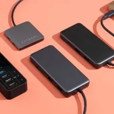 Kilka hubów USB-C i rozgałęźnik USB-A na tle w kolorze brzoskwiniowym.
